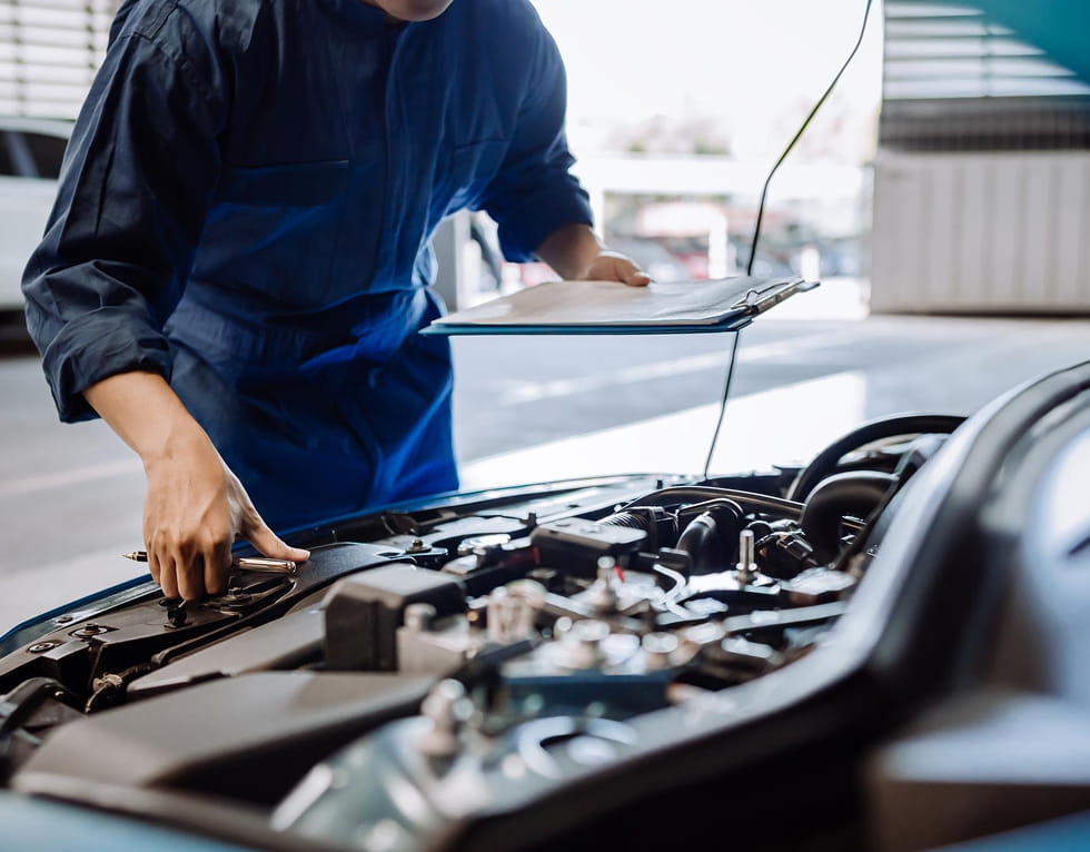 Automechaniker Untersucht Den Motorraum Mit Klemmbrett Und Stift In Der Hand.