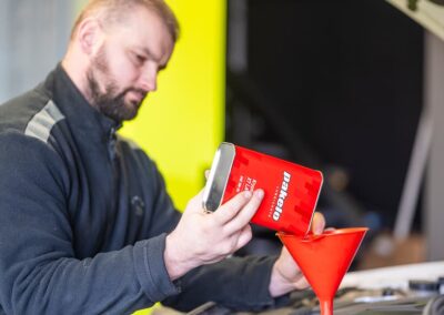 Kfz Mechaniker Gießt Motoröl Aus Rotem Kanister Mit Trichter Ein