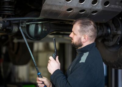 Kfz Mechaniker Inspiziert Fahrzeugunterseite Auf Hebebühne Mit Taschenlampe